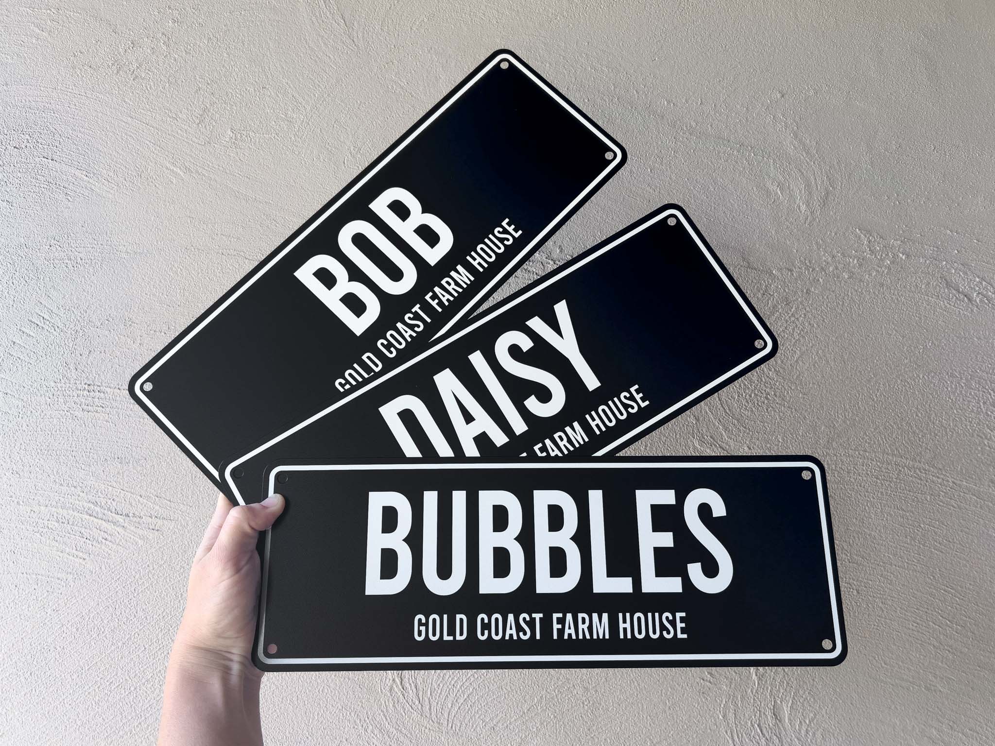 Three black name signs with white text that read 'BOB', 'DAISY' & 'BUBBLES' at 'GOLD COAST FARM HOUSE'.