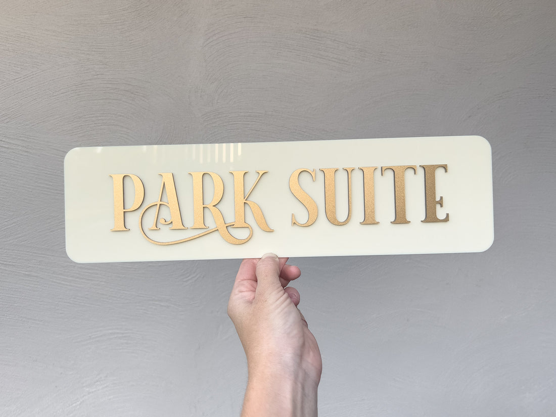 Custom acrylic door sign that reads 'Park Suite' in metallic gold on a glossy beige plate.