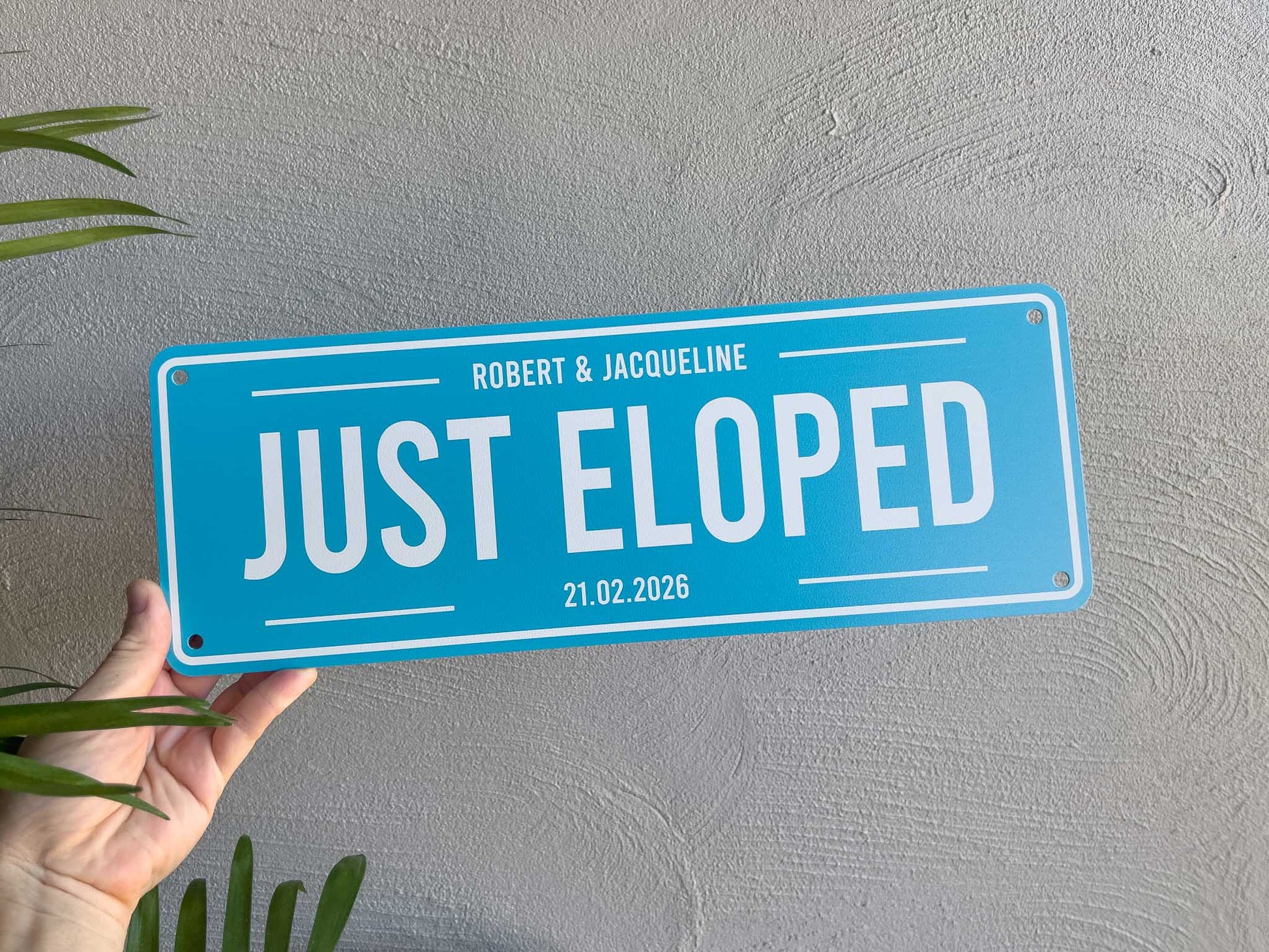 A personalised coastal blue sign with white text that reads 'Just Eloped 21.02.2026'.
