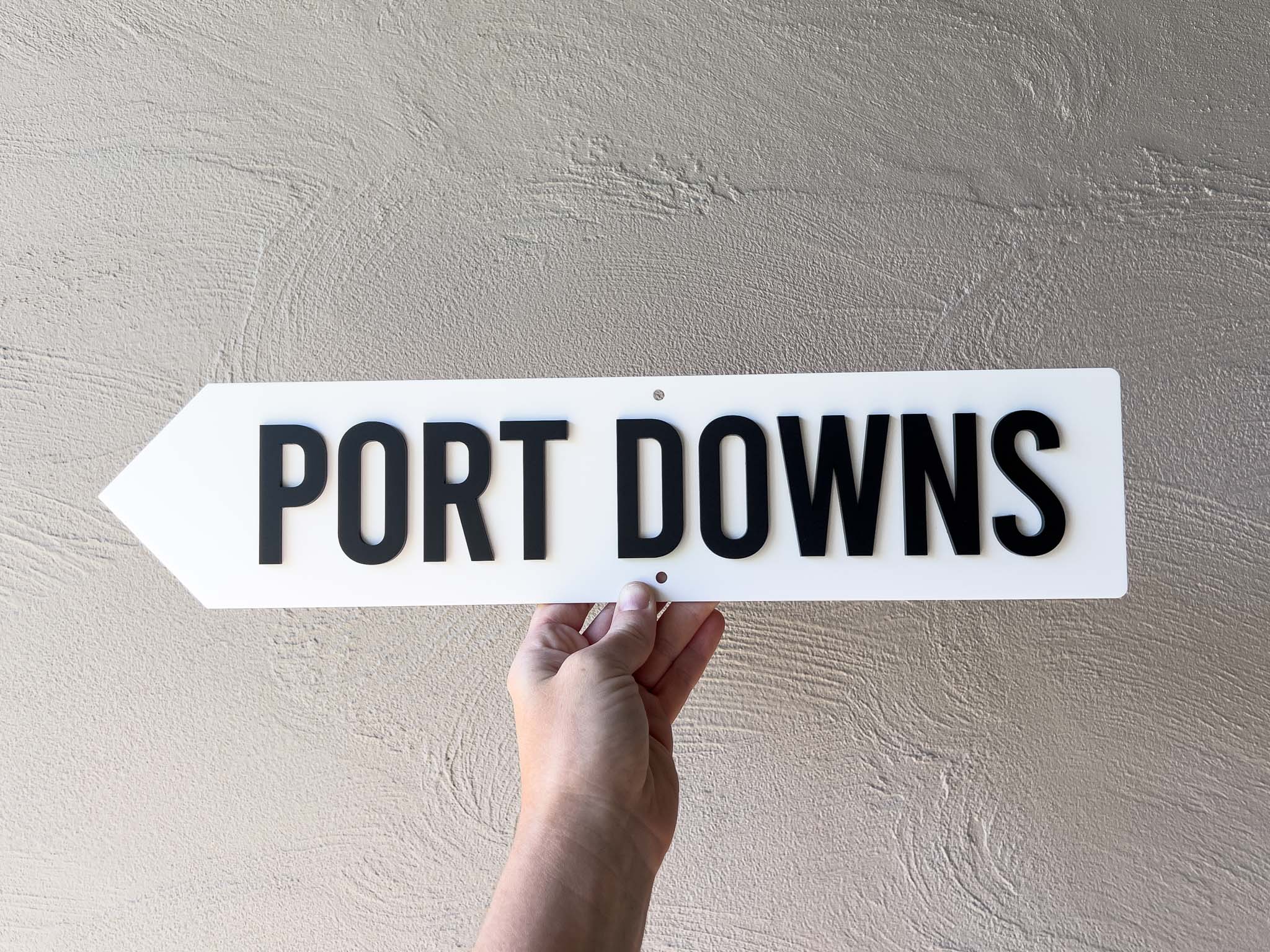 A custom mini 3D acrylic direction sign in white with black text that reads 'PORT DOWNS'.