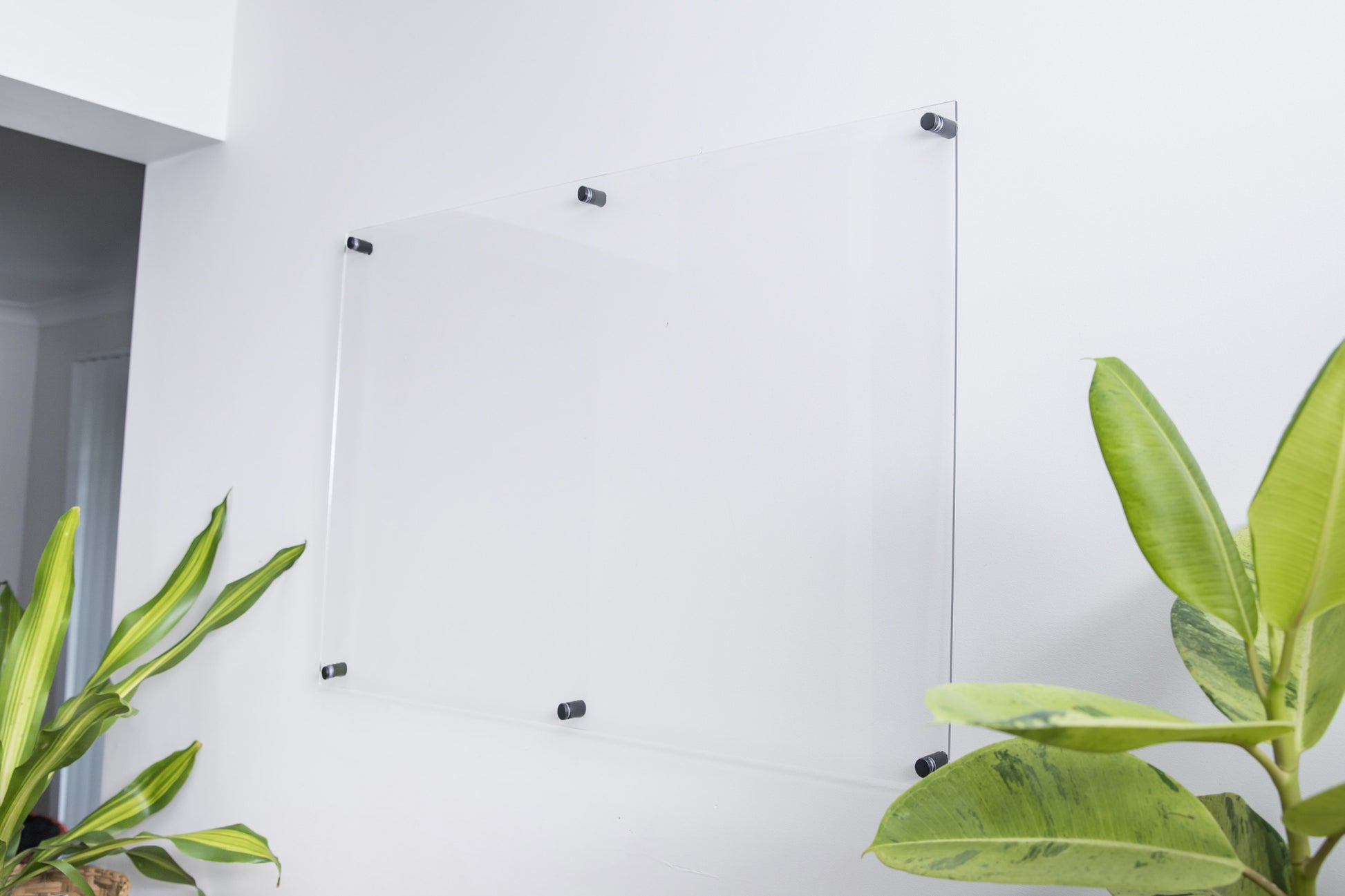 Modern interior clear acrylic wall planner mounted on a white wall with black wall mounts