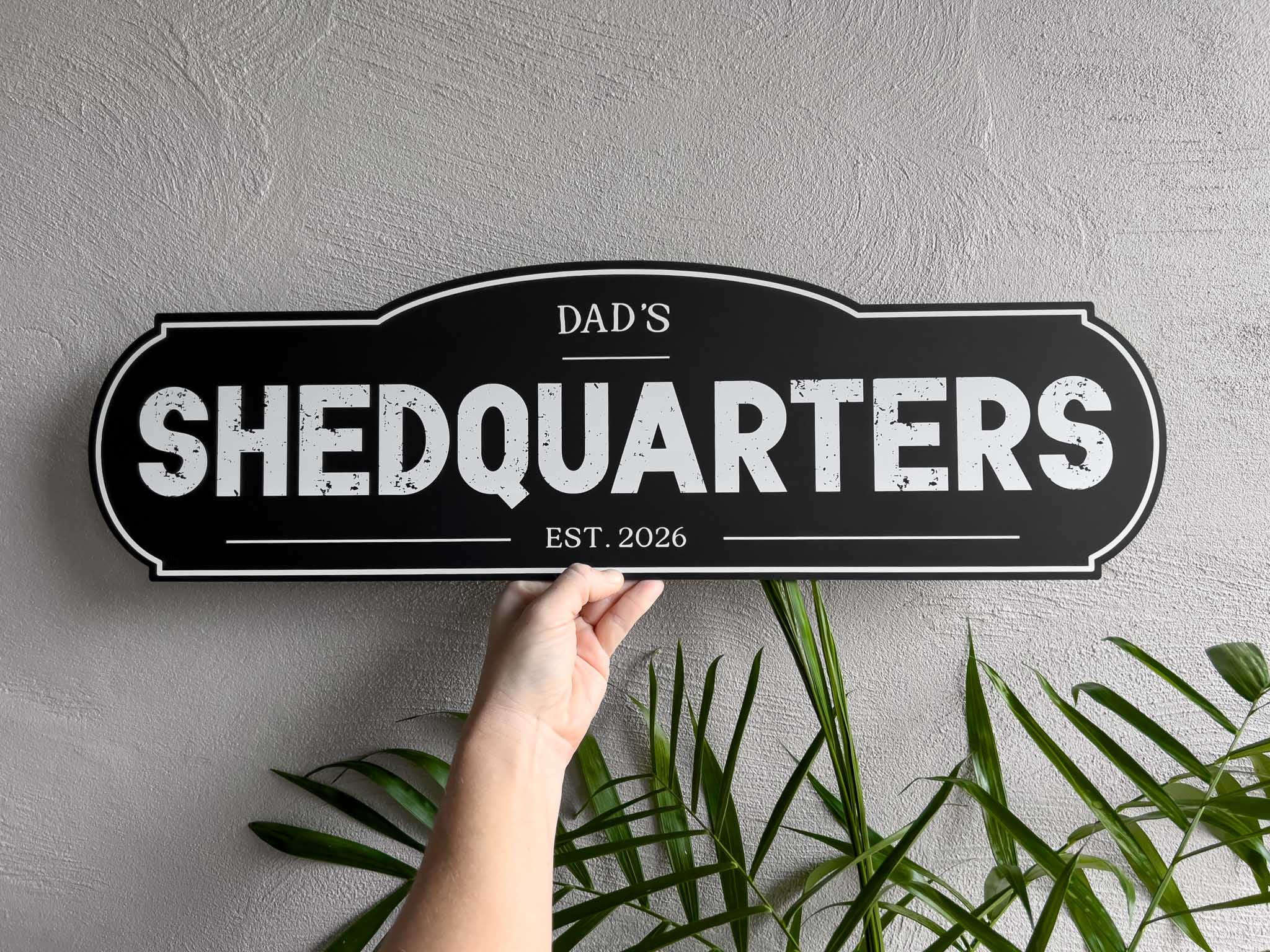 A unique custom printed vintage sign that reads 'Dad's SHEDQUARTERS Est. 2026', in black with white text.